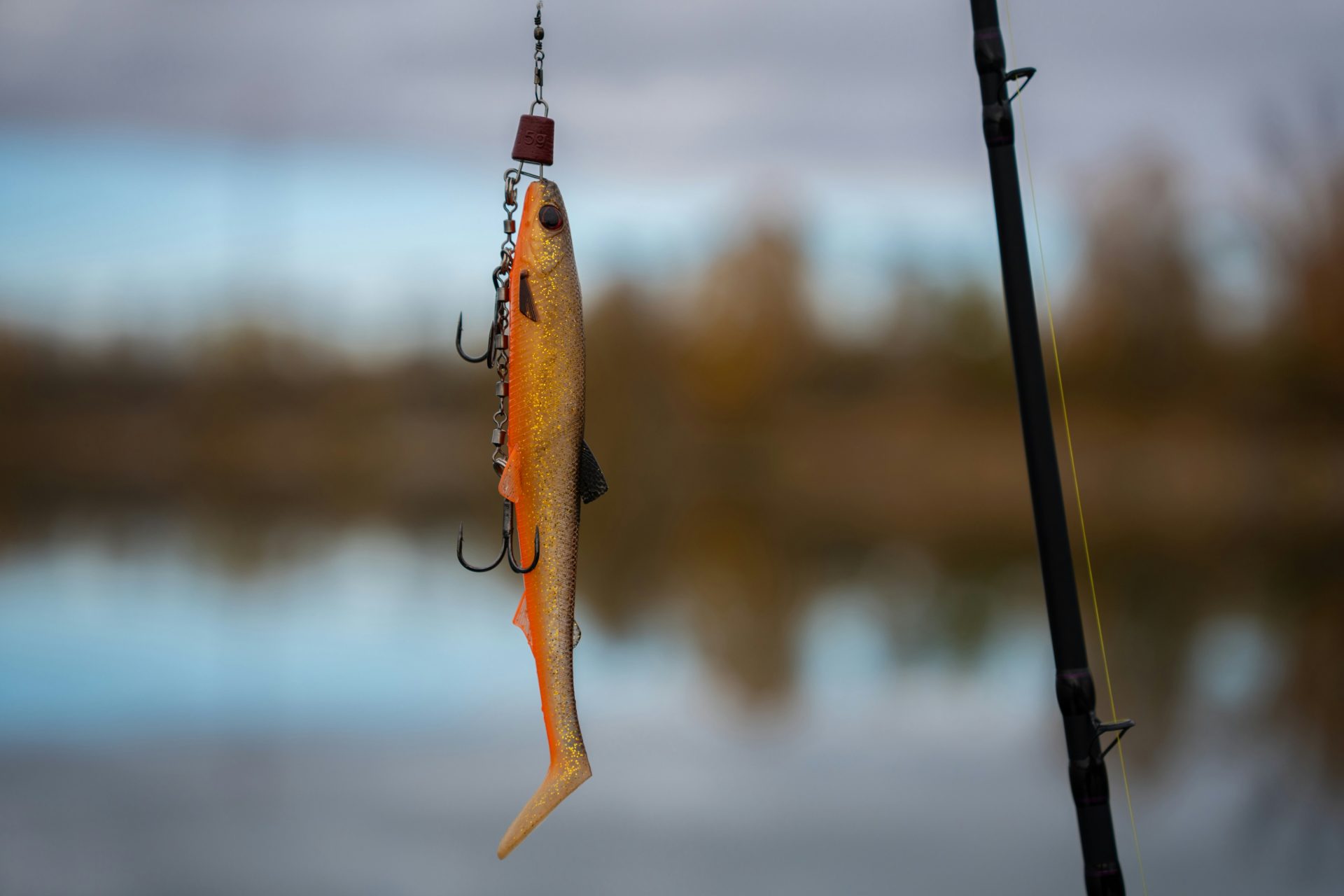 Fishing lure with treble hooks hanging from rod